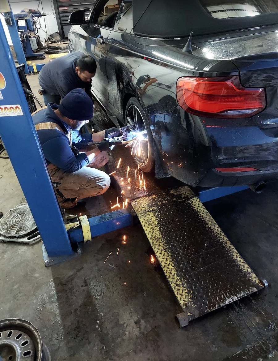 Llantera Del Norte mechanics performing tire and wheel service on a BMW in Aurora CO — skilled auto repair team at work